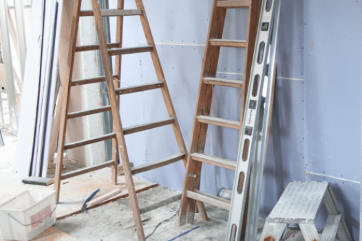 room in construction showing multiple ladders leaning against the wall